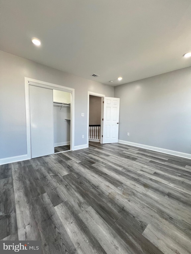 unfurnished bedroom featuring dark hardwood / wood-style flooring and a closet