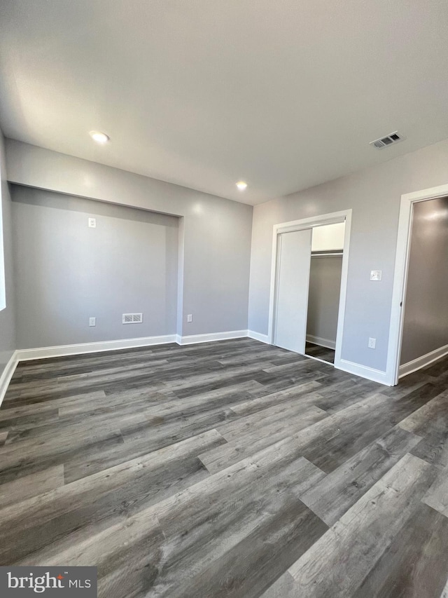 unfurnished bedroom with dark wood-type flooring and a closet