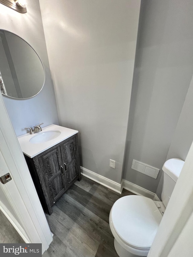 bathroom with toilet, vanity, and wood-type flooring