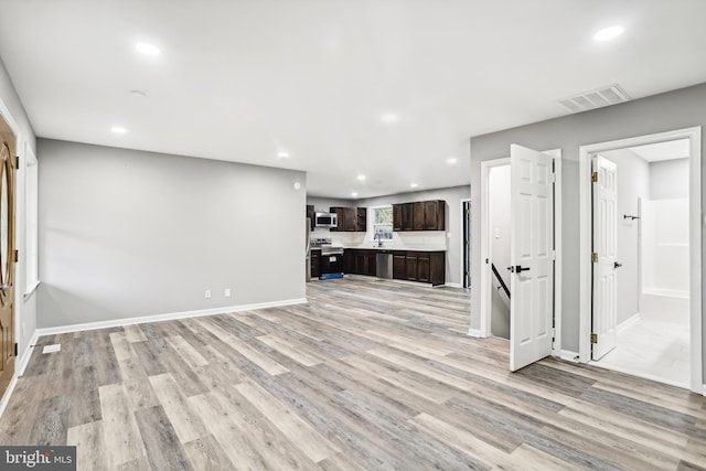 unfurnished living room featuring sink and light hardwood / wood-style flooring