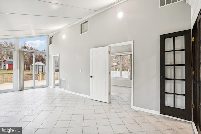 tiled empty room featuring french doors and a towering ceiling