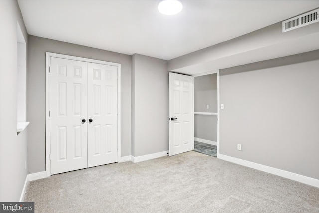 unfurnished bedroom with light colored carpet and a closet