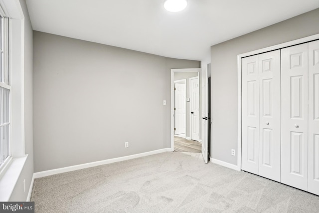 unfurnished bedroom featuring a closet and light colored carpet