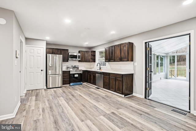 kitchen featuring plenty of natural light, dark brown cabinetry, light wood-type flooring, and appliances with stainless steel finishes