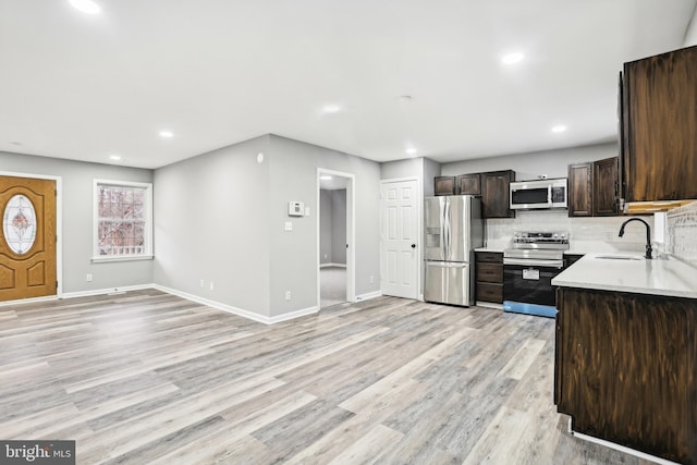 kitchen featuring dark brown cabinets, light hardwood / wood-style floors, sink, and appliances with stainless steel finishes