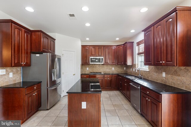 kitchen with light tile patterned floors, a center island, stainless steel appliances, and sink