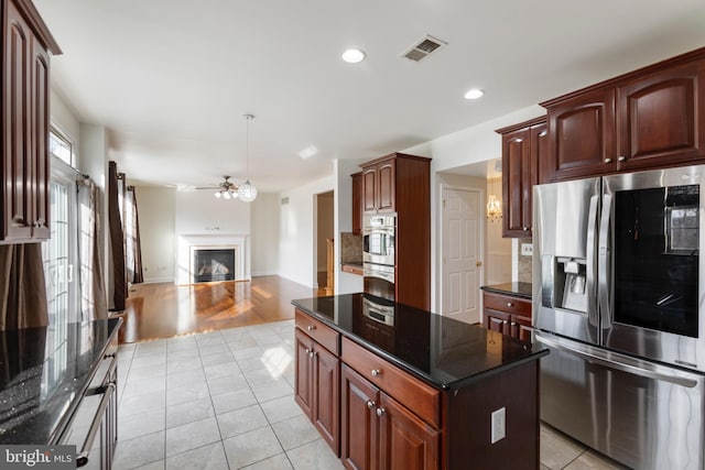 kitchen featuring a center island, backsplash, dark stone countertops, light wood-type flooring, and stainless steel appliances