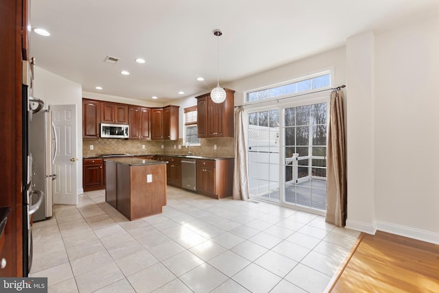 kitchen with decorative backsplash, stainless steel appliances, decorative light fixtures, a center island, and light tile patterned flooring