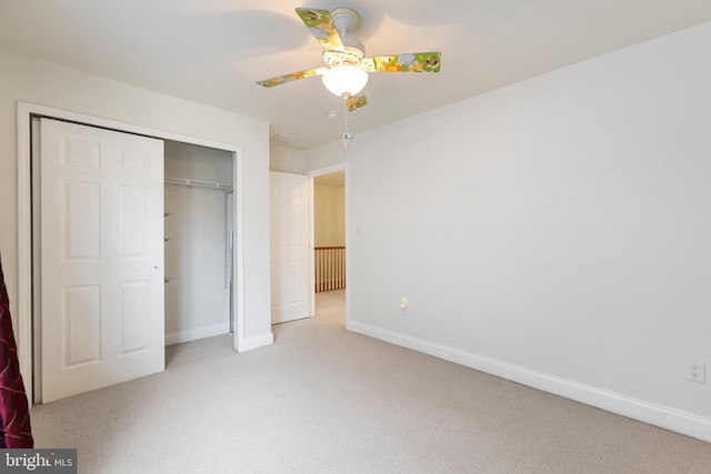 unfurnished bedroom with ceiling fan, light colored carpet, and a closet