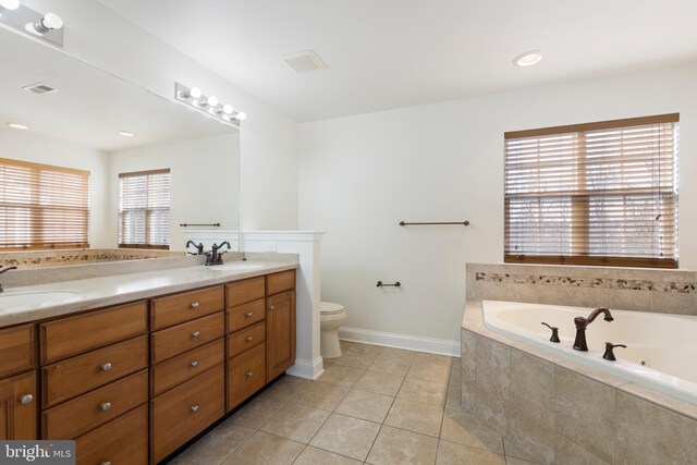 bathroom featuring tile patterned floors, vanity, a relaxing tiled tub, and toilet