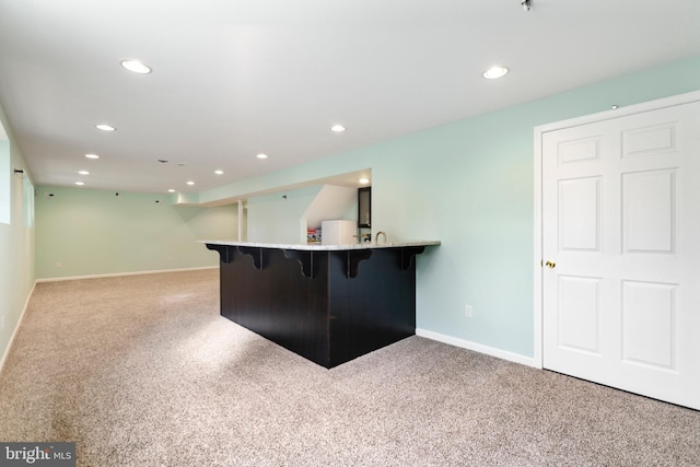 kitchen featuring a breakfast bar area, kitchen peninsula, white fridge, and light colored carpet