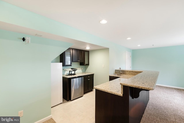 kitchen featuring light carpet, kitchen peninsula, light stone counters, sink, and a breakfast bar area