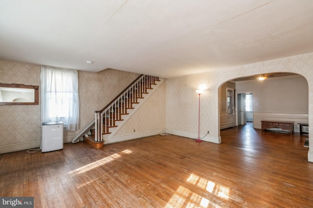 unfurnished living room featuring wood-type flooring, ceiling fan, and a baseboard heating unit