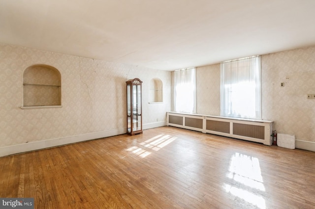 spare room featuring hardwood / wood-style floors and radiator heating unit