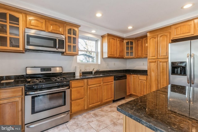 kitchen with sink, light tile patterned floors, dark stone counters, and appliances with stainless steel finishes