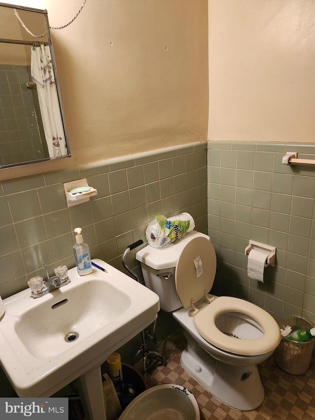 bathroom featuring sink, toilet, tile walls, and tile patterned floors