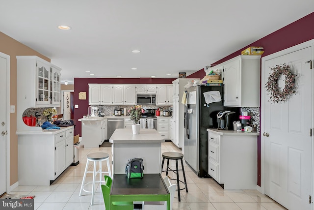 kitchen with stainless steel appliances, white cabinetry, tasteful backsplash, a breakfast bar area, and a center island