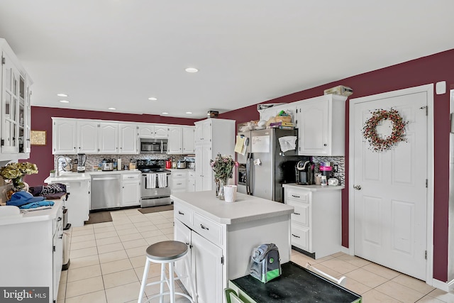 kitchen featuring white cabinetry, decorative backsplash, a center island, and stainless steel appliances