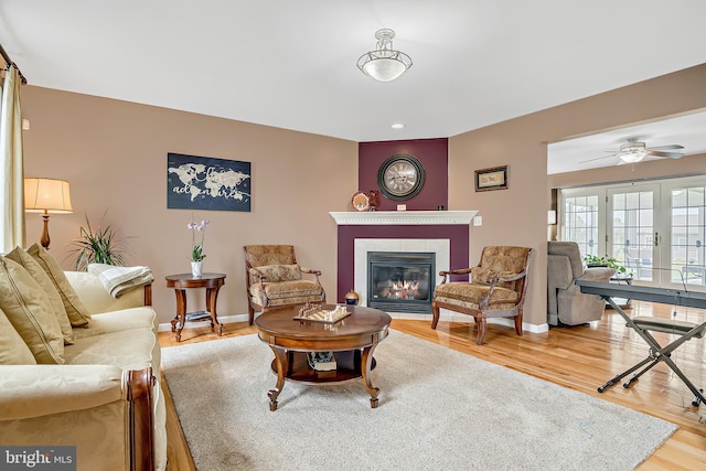 living room featuring hardwood / wood-style floors, a tile fireplace, and ceiling fan