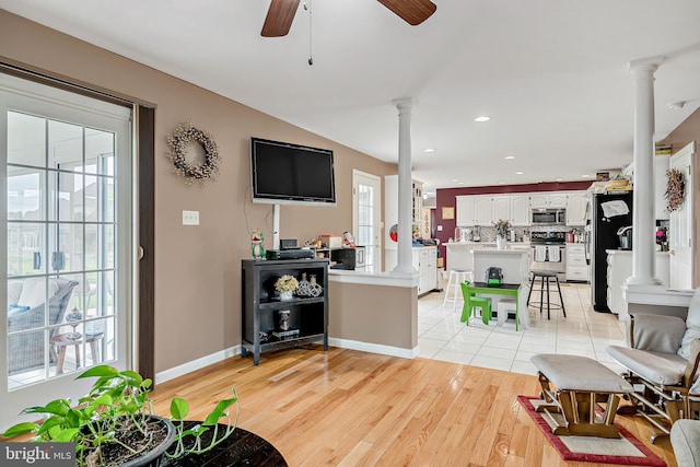 living room with ceiling fan, light wood-type flooring, and decorative columns