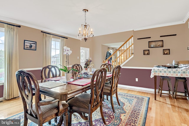 dining area with a notable chandelier, light hardwood / wood-style floors, and crown molding