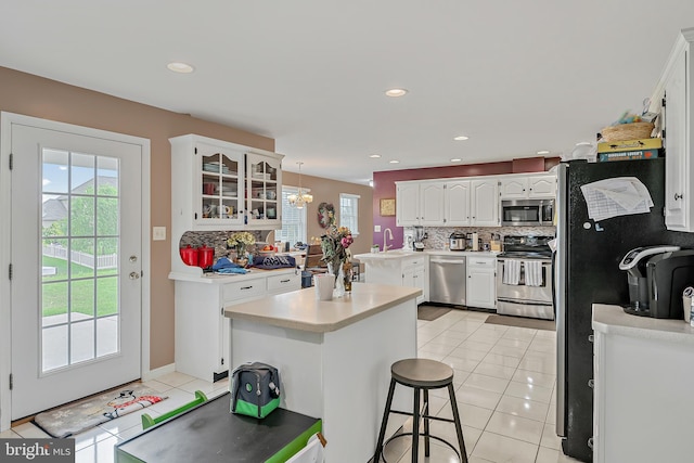 kitchen with white cabinetry, appliances with stainless steel finishes, decorative light fixtures, light tile patterned floors, and a breakfast bar area