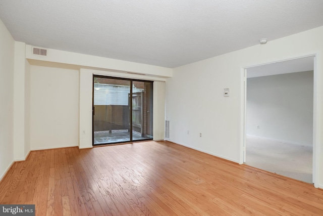 empty room featuring a textured ceiling and light hardwood / wood-style flooring