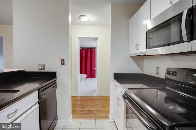 kitchen featuring light tile patterned floors, a textured ceiling, white cabinetry, and black appliances