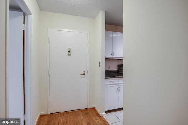 hall with light hardwood / wood-style floors and a textured ceiling