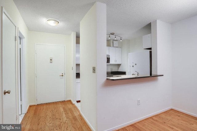 corridor featuring a textured ceiling and light hardwood / wood-style floors