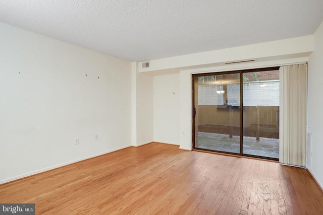 empty room with a textured ceiling and light wood-type flooring