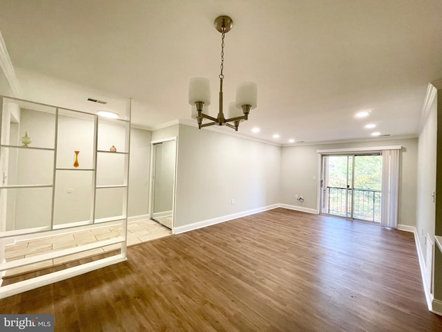 empty room featuring an inviting chandelier, wood-type flooring, and crown molding