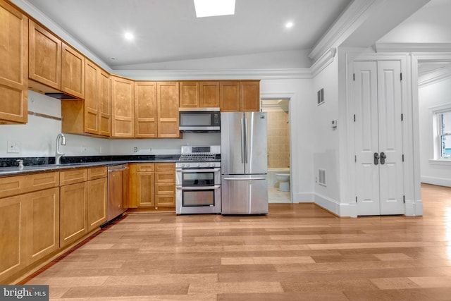 kitchen with appliances with stainless steel finishes, light wood-type flooring, a sink, dark countertops, and baseboards