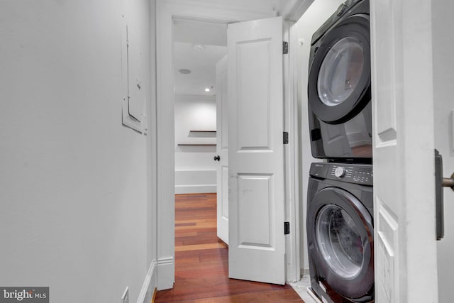 washroom with stacked washing machine and dryer and dark wood finished floors