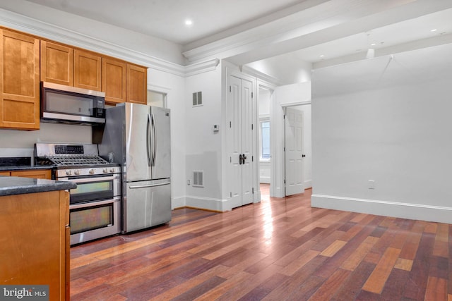 kitchen with appliances with stainless steel finishes, dark hardwood / wood-style floors, and ornamental molding