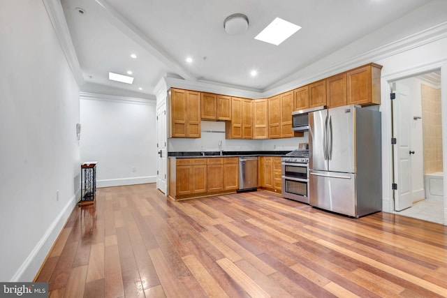 kitchen featuring stainless steel appliances, dark countertops, light wood-style floors, a sink, and recessed lighting