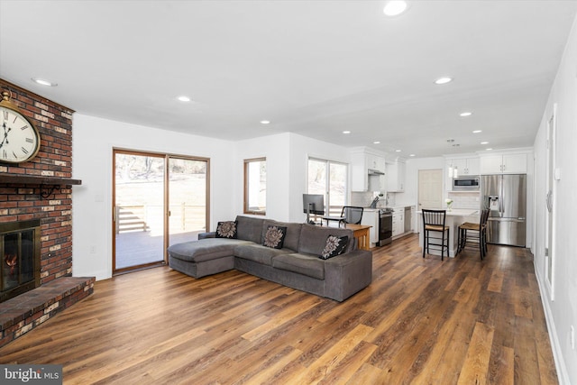 living room with dark wood-type flooring and a brick fireplace