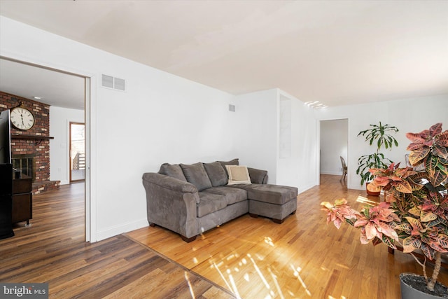 living room featuring hardwood / wood-style flooring and a brick fireplace