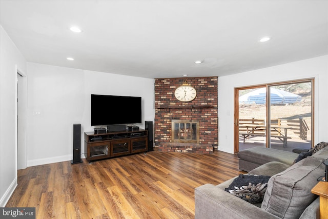 living room with a brick fireplace and hardwood / wood-style flooring