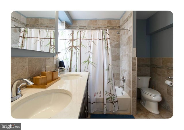 full bathroom featuring tile patterned flooring, toilet, shower / tub combo with curtain, vanity, and tile walls