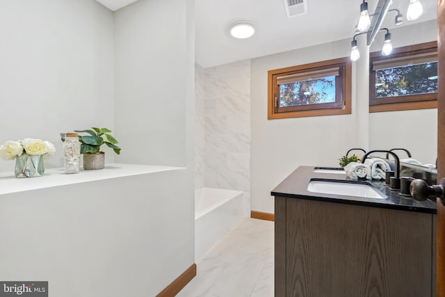 bathroom featuring tiled shower / bath and vanity