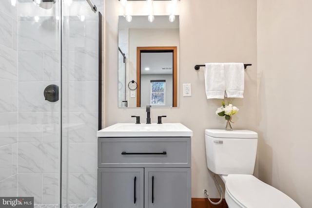 bathroom featuring toilet, vanity, and a shower with shower door