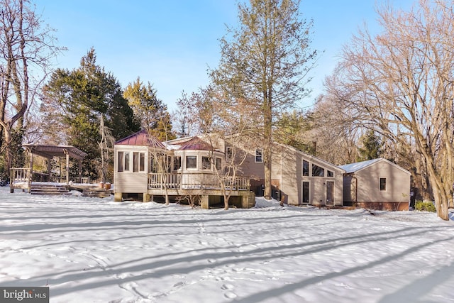 snow covered back of property featuring a pergola and a deck