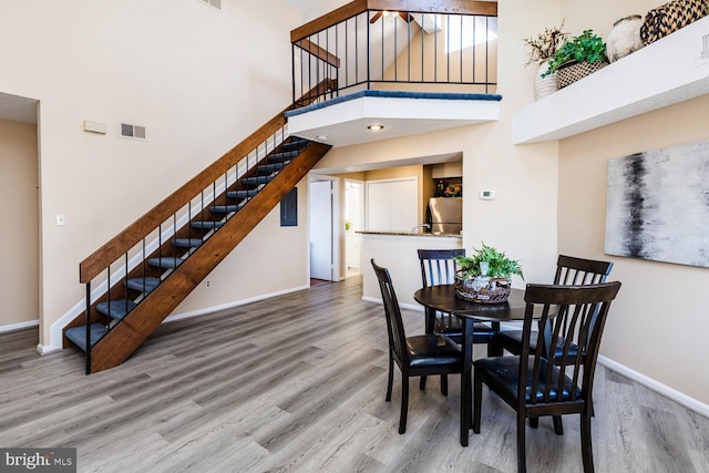 dining area featuring wood-type flooring and a high ceiling