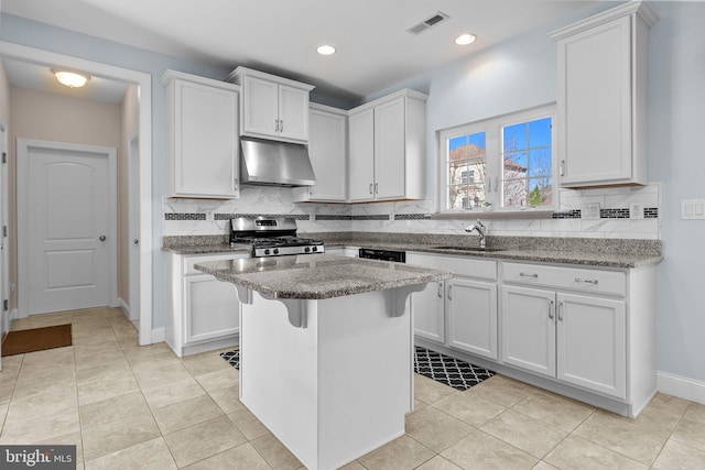 kitchen with gas stove, light stone countertops, sink, and white cabinets