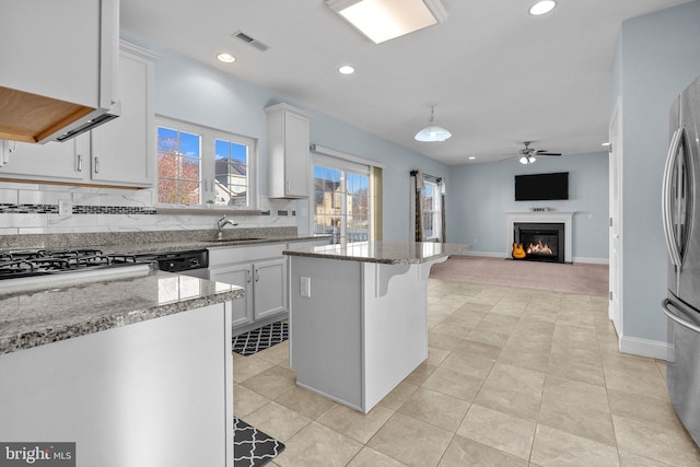 kitchen with sink, light stone counters, a kitchen breakfast bar, and white cabinets