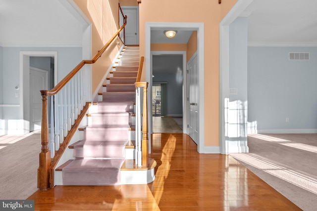 stairs with hardwood / wood-style flooring and ornamental molding