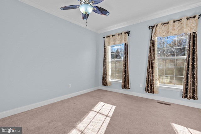 carpeted empty room featuring ceiling fan, crown molding, and plenty of natural light