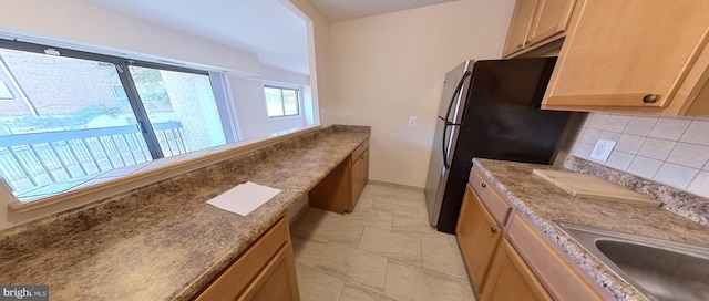 kitchen with sink, backsplash, and stainless steel refrigerator