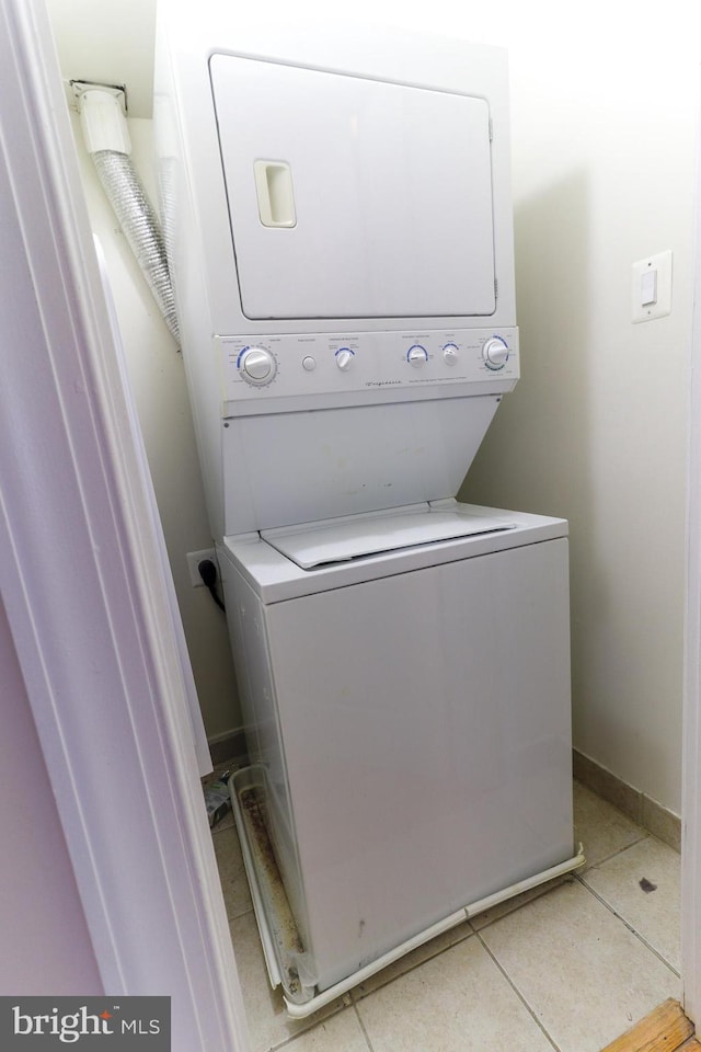 laundry room with light tile patterned floors and stacked washer / dryer